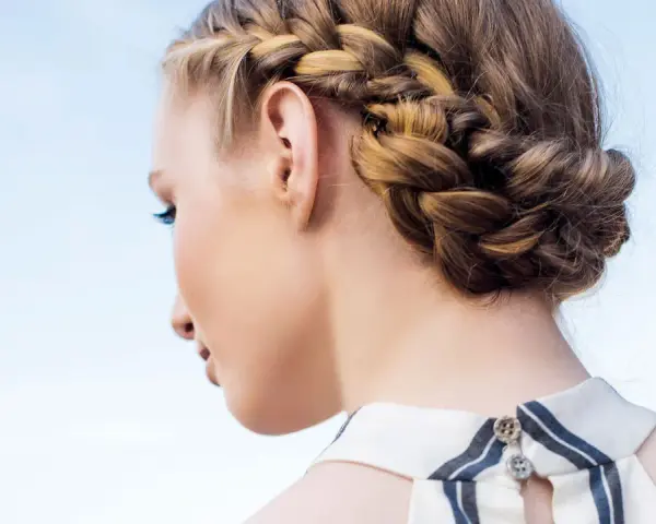 Peinados con trenzas: una mujer con un recogido trenzado elegante, ideal para un día soleado.