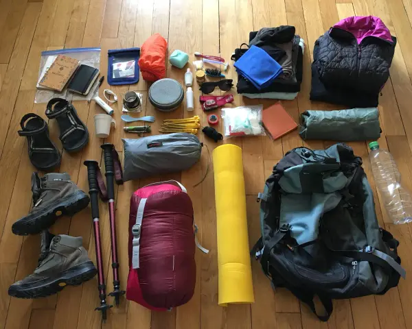Préparatifs pour une randonnée : chaussures, bâtons, sac de couchage, sac à dos, vêtements, trousse de toilette, gourde. Voici comment ranger son sac de randonnée.
