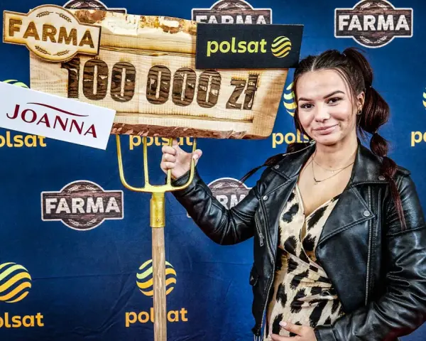 Joanna z "Farmy" trzyma widły i tablicę z napisem "100 000 zł".