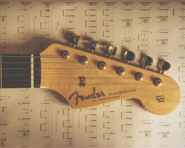 Głowa gitary Fender Stratocaster na tle nut. Idealne nuty na gitarę dla początkujących.