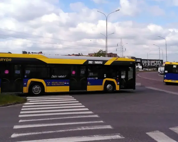 Autobus 262 z napisem "Dużo radości!" zbliża się do przejścia dla pieszych. Sprawdź autobus 136 rozkład jazdy.