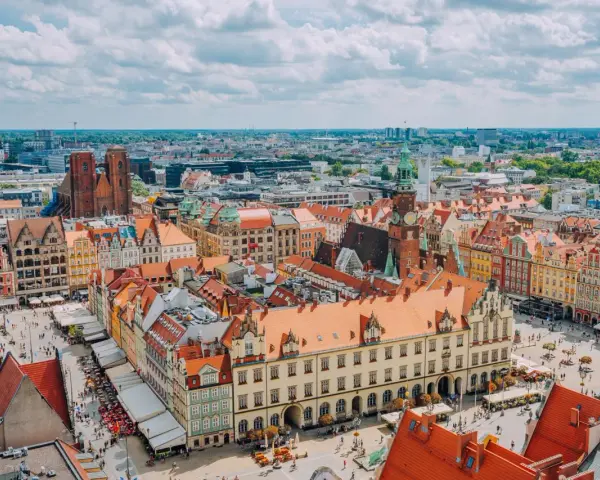 Wrocław słynie z kolorowych kamienic na Rynku i wież kościelnych. Widok z lotu ptaka na tętniące życiem miasto.