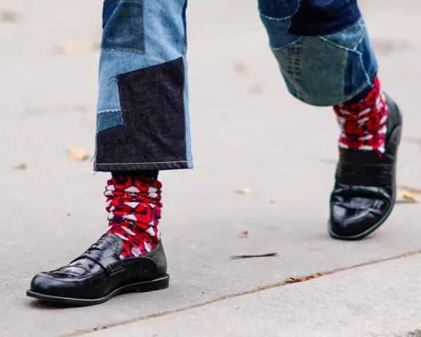 Pantaloni patchwork e scarpe eleganti con calzini rossi a fantasia, un look audace per sfidare le scarpe senza calze in inverno.