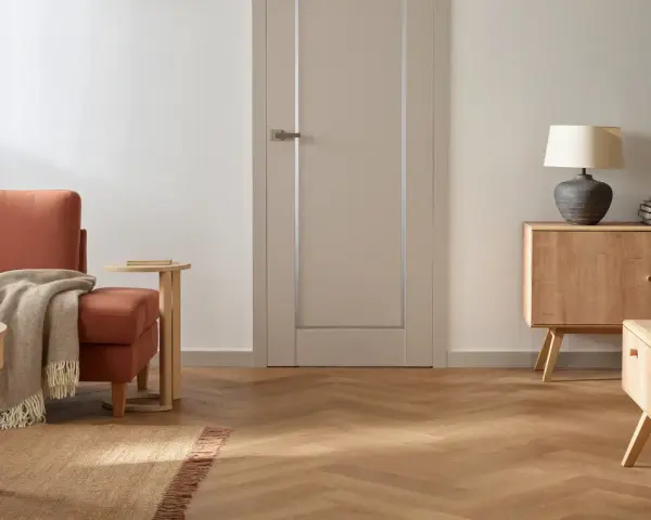 Nowoczesne wykończenie drzwi wewnętrznych w stonowanym kolorze, idealnie komponuje się z drewnianą podłogą i meblami.