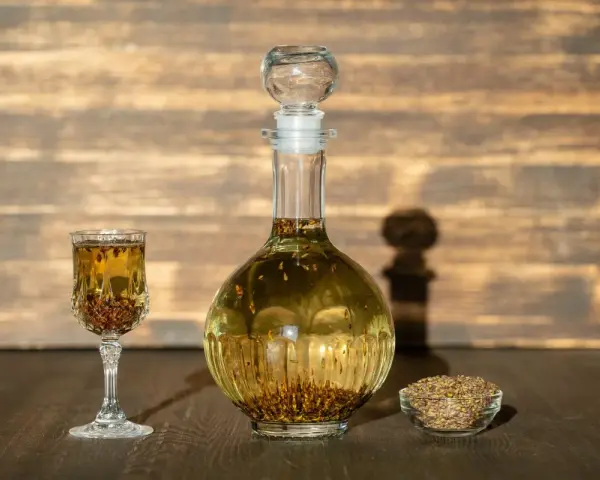 Wódka z pieprzem przepis: nalewka w karafce i kieliszku, obok miseczka z ziarnami pieprzu.