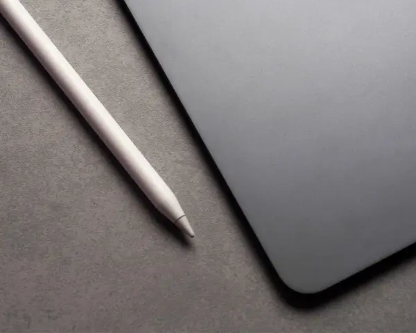 Apple Pencil liegt neben einem iPad mit drei leuchtenden Punkten.