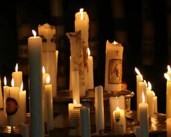 Viele Kerzen brennen in der Dunkelheit, einige mit Bildern und Kreuzen verziert. Ein stimmungsvolles Bild, das an Maria Lichtmess erinnert.
