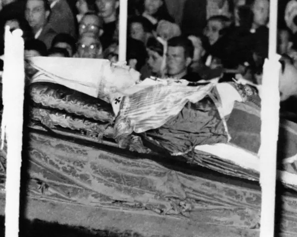Pius XII w szatach, przygotowany do balsamowania. Tłum ludzi w tle.