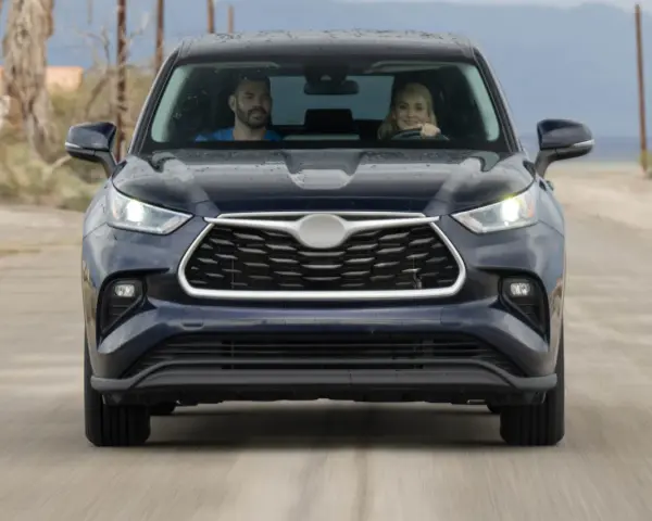 A couple in a dark SUV drive on a dirt road. They might be wondering how long to wait for jump start if the car dies.