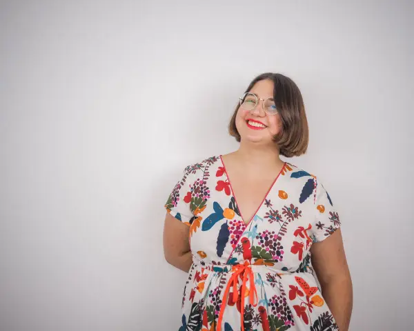 Une femme souriante porte une robe d'été colorée, un modèle inspiré d'un patron gratuit de robe Charlotte.