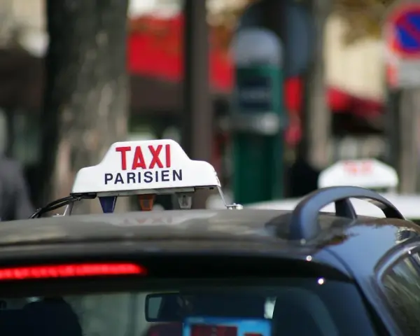 Ein Taxi in Frankreich, mit der Aufschrift "TAXI PARISIEN", wartet auf Fahrgäste.