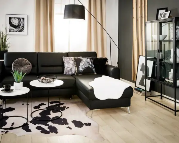 Nowoczesny salon z czarną kanapą i dywanem w cętki. Inspiracje dla odważnych aranżacji.