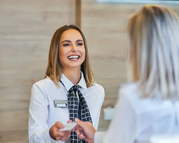 Una sorridente hostess di terra consegna una tessera a un cliente.