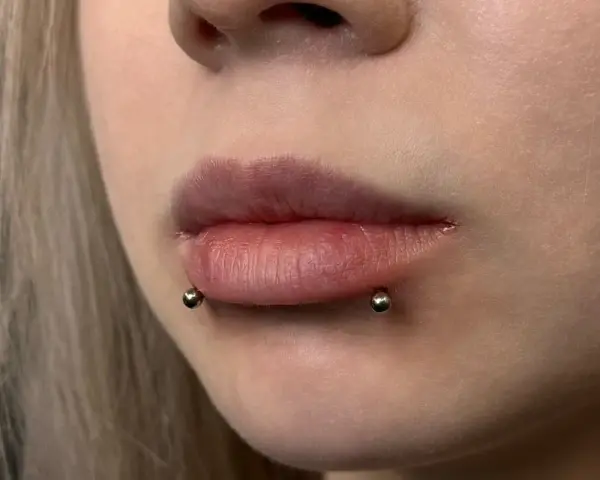 Cyber bites piercing na ustach, podkreślający ich kształt.