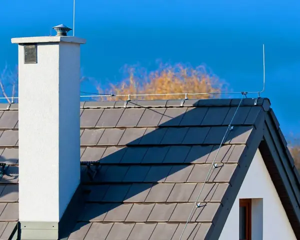 Na dachu domu widoczna jest instalacja odgromowa, chroniąca przed uderzeniami pioruna.