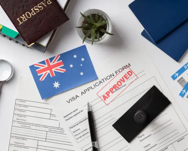 Paszport, formularz wizowy z pieczątką "APPROVED", flaga Australii, bilety lotnicze.
