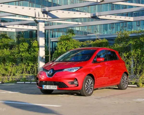 Czerwony Renault Zoe, elektryczny samochód miejski, gotowy do jazdy. Jego imponujący zasięg pozwala na swobodne podróżowanie po mieście i poza nim.