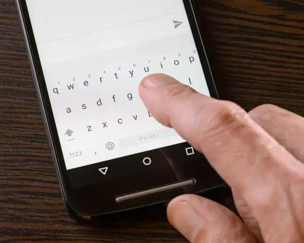Palec naciska klawisz "Polski" na klawiaturze telefonu, aby ustawić polskie znaki w SMS.