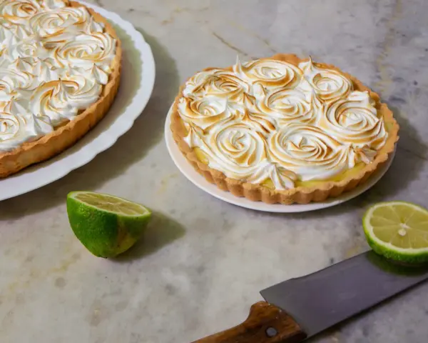 Dos deliciosas tartas de limón con merengue tostado, listas para ser cortadas.