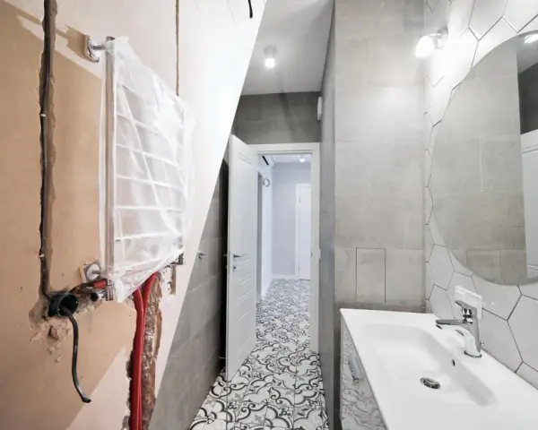 Bagno in ristrutturazione con impianto idraulico a vista, pronto per la detrazione 65. Pavimento decorato e lavabo moderno.