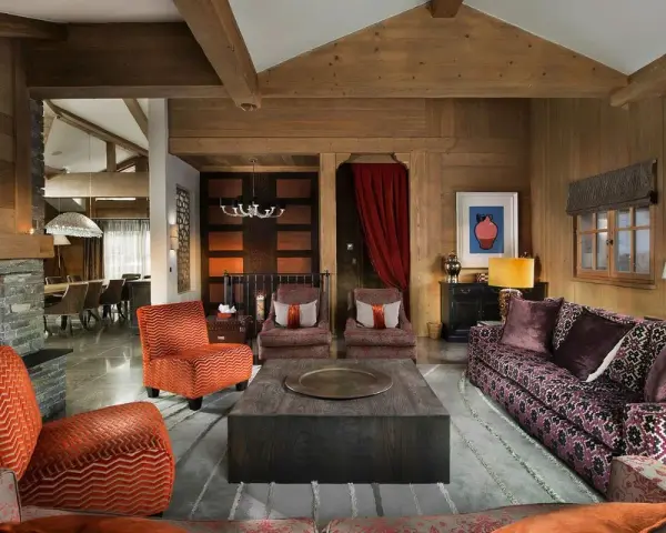 Arredare taverna con stile: divani viola, poltrone arancioni e un grande tavolino centrale in legno.
