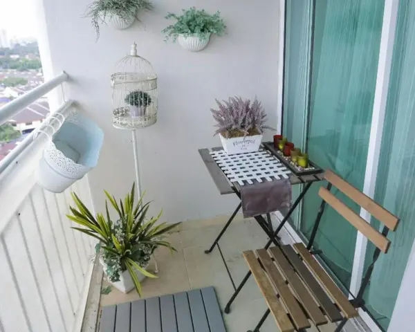 Schöne Balkon Ideen: Ein kleiner Tisch mit Stühlen, Pflanzen in Körben und eine dekorative Vogelkäfig schaffen Gemütlichkeit.