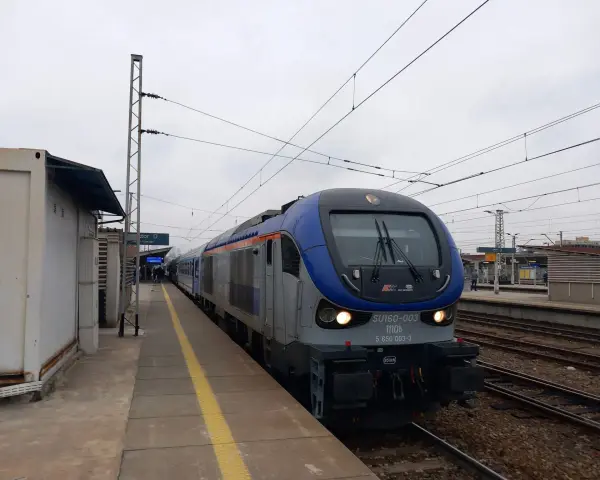 Lokomotywa PKP Intercity SU160-003 na torach kolejowych przy peronie.