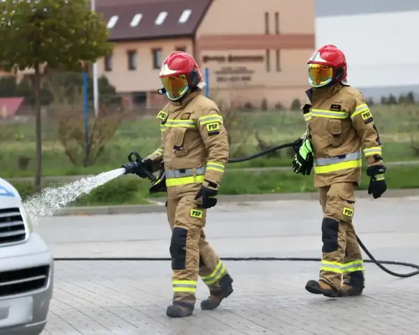 Strażacy w akcji, jeden z węża wodnego. Zastanawiasz się, ile zarabia strażak? To praca pełna wyzwań.