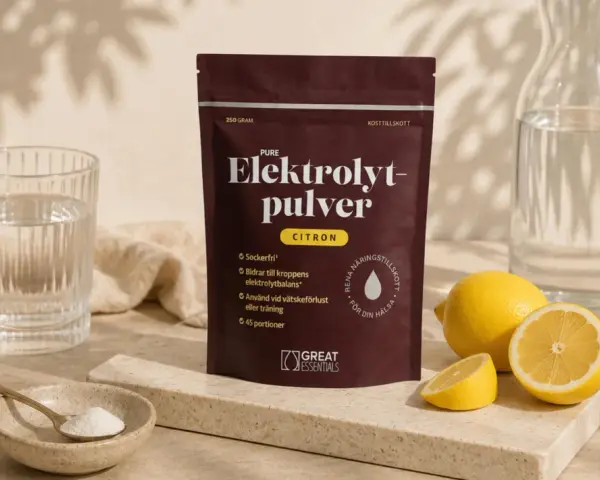En påse elektrolytpulver med citronsmak, bredvid färska citroner, ett glas vatten och en skål med pulver. Selen finns i för att återställa vätskebalansen.