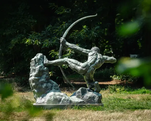 La sculpture de l'archer, une œuvre d'Antoine Bourdelle, se dresse fièrement dans un jardin verdoyant, capturant l'instant d'une tension parfaite.