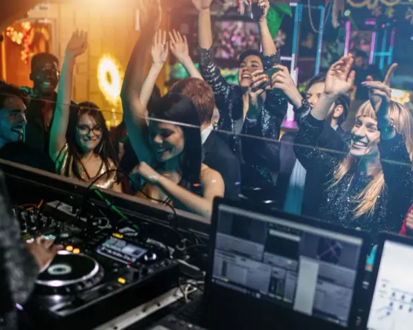 Feiernde Menschen tanzen im Club, während ein DJ auflegt. Eine druckbare muttizettel vorlage zum ausdrucken wäre hier perfekt für die nächste Party!