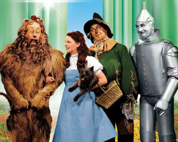 Il leone codardo, Dorothy con Toto, lo spaventapasseri e l'uomo di latta camminano sul sentiero di mattoni gialli. Il linguaggio dei colori evoca un mondo magico.