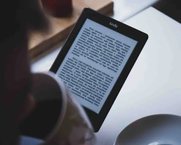 Osoba czyta książkę w formacie kindle. Na ekranie widoczny jest tekst powieści.