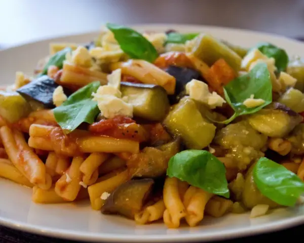 Pyszne danie z makaronem, bakłażanem i pomidorami, posypane serem i bazylią. Idealne na Pasta alla Norma przepis.
