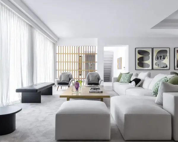 Elegante salón pintado en gris, con sofás blancos, sillones grises y arte abstracto.