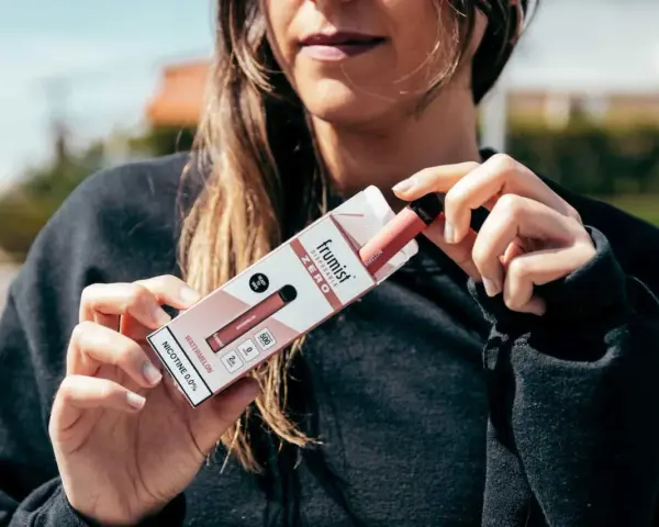 Una persona sostiene una caja de vapeador desechable Frumiist Zero sabor sandía.