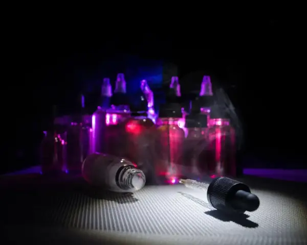 Gotas de nicokit como usar: frascos de líquido para vapear con luz púrpura y vapor.