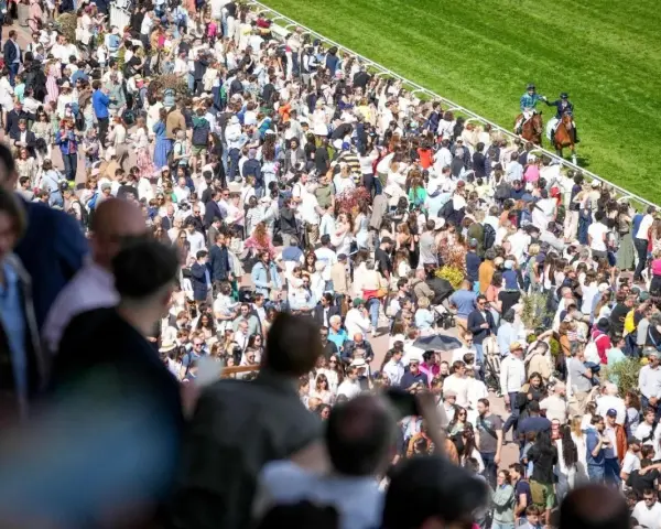 Foule nombreuse sur un hippodrome en France, spectateurs massés pour une course de chevaux.