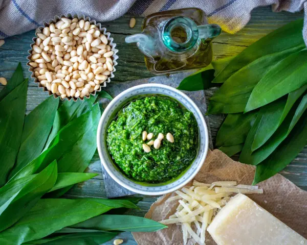 Pesto z czosnku niedźwiedziego, orzechów pinii i oliwy. Obok kawałek sera, który może być alternatywą, jaki ser do pesto zamiast parmezanu?