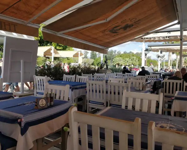 Uroczy ogródek restauracyjny w Larnace z niebiesko-białymi obrusami. Idealne miejsce, by dowiedzieć się, co i gdzie zjeść w Larnace.