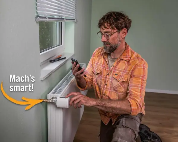Mann installiert smarten Thermostat am Heizkörper, um Heizkosten zu sparen. "Mach's smart!