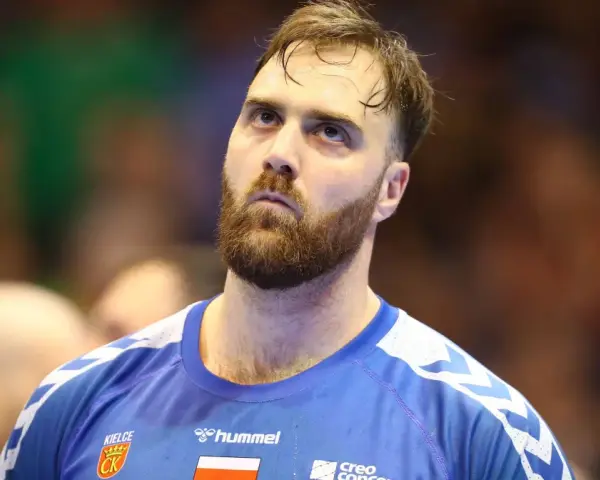 Andreas Wolf, zamyślony zawodnik w niebieskiej koszulce z herbem Kielc, patrzy w górę.