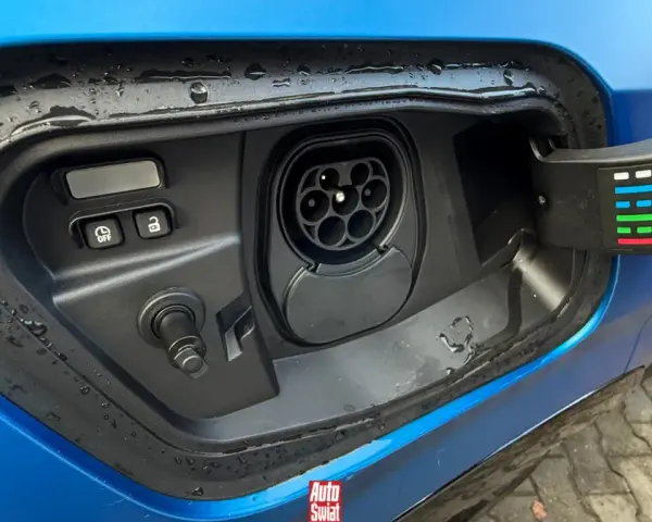 Gniazdo ładowania w niebieskim samochodzie. To pokazuje, co to jest plug-in hybrid – samochód, który można ładować z sieci.