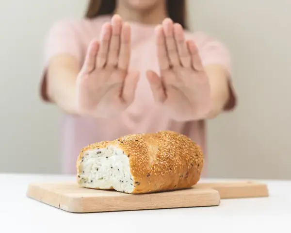 Osoba odrzuca chleb, sygnalizując uczulenie na gluten i laktozę objawy.