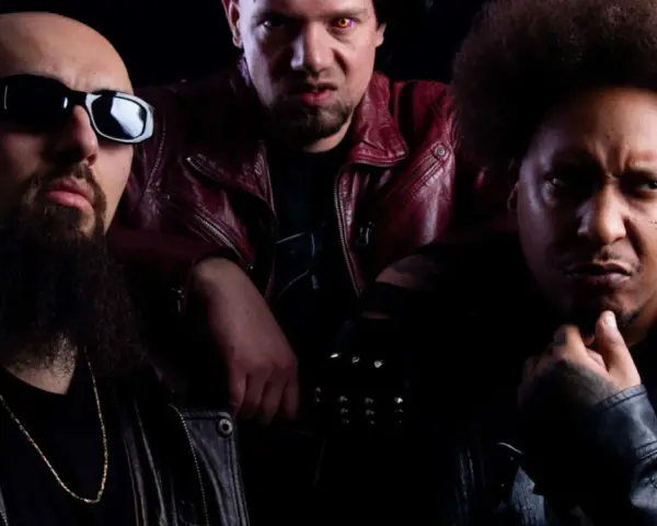Trois hommes au look sombre, dont un avec des lunettes de soleil et une barbe, un autre avec des yeux jaunes et une veste rouge, et le troisième avec une afro. Un trio dope dod.