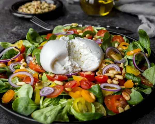 Frischer Salat mit Burrata, Tomaten, Zwiebeln und Pinienkernen. Perfekt für eine leichte Mahlzeit, auch in der Schwangerschaft.