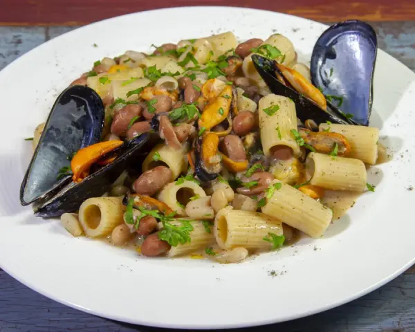 Piatto di pasta fagioli e cozze, con rigatoni, fagioli borlotti e cannellini, cozze nere e prezzemolo tritato.