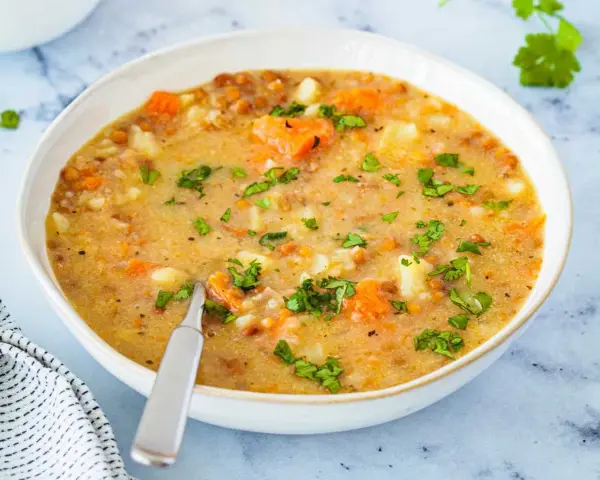 Un tazón de sopa de lentejas casera con zanahorias y patatas, perfecto para aprender como hacer lentejas.