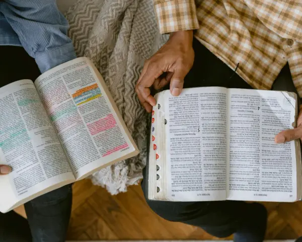 Dwie osoby czytają Biblię, zaznaczając ważne cytaty. Widać fragmenty z Księgi Przysłów.