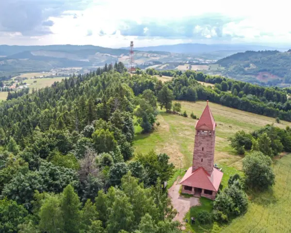 Wieża widokowa w górach zaprasza na podziwianie krajobrazu. W oddali widać maszt telekomunikacyjny.